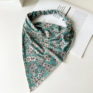 Detail of green floral cotton triangle headscarf with elastic band on white background