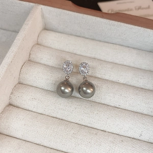 Detail shot of silver drop earrings with oval zircon crystals and grey pearls