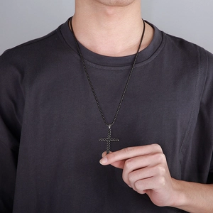 Detail of a black textured cross pendant necklace worn by a male model for daily styling
