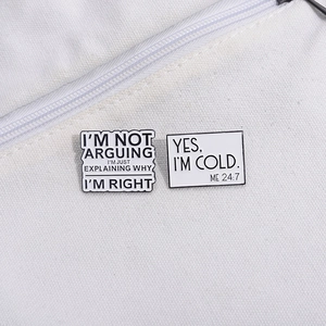 Close-up of funny quote enamel pins on white canvas bag showing metal texture