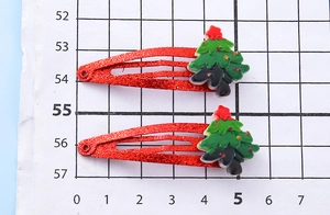 Detail of red glitter Christmas tree hair clips with 5cm scale measurement on grid