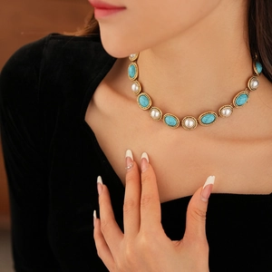 Detail of vintage necklace featuring turquoise oval stones and white pearls on golden chain