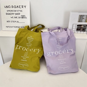 Détail de sacs fourre-tout en toile vert moutarde et lilas avec typographie florale blanche