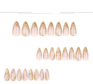 Macro view of short almond press-on nails with nude base and 3D gold texture details