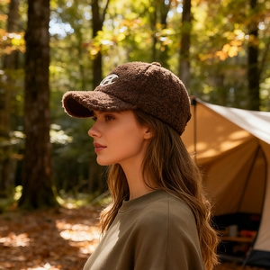 Brown fleece baseball cap with C embroidery shown in an outdoor camping setting