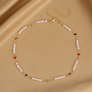 Macro view of gold-tone necklace with colorful gemstones and pearls on silk fabric