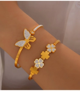 Close-up of gold butterfly and clover bangle bracelets with pavé diamond accents