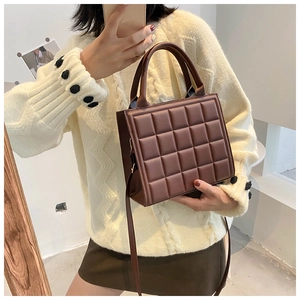 Deep brown quilted square handbag with retro embroidery shown in a side hand-carry pose