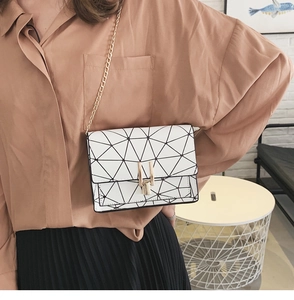 Detailed view of a white geometric crossbody bag with a gold chain strap worn by a model
