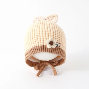 Detail of baby knit hat showing beige crochet flower and leather label with bow ties