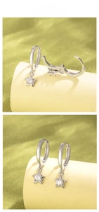 Détails de boucles d'oreilles étoile argentées avec zircon brillant sur support vert clair
