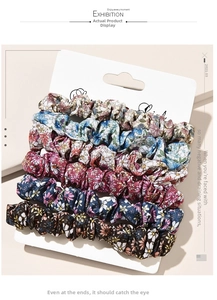 Detail of five floral fabric scrunchies in various colors on a white display card