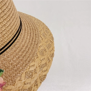 Close-up of woven straw sun hat showing intricate texture, wavy edge, and floral detail