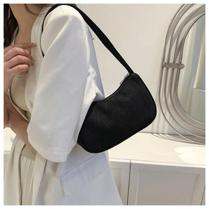 Detail of minimalist black corduroy shoulder bag with textured stripe finish on model