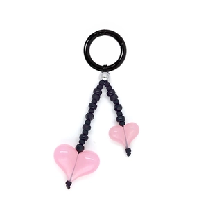 Close-up of black beaded key chain with translucent pink heart pendants on white background