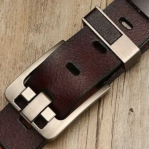 Close-up of vintage brown leather belt featuring a brushed silver buckle on wood texture
