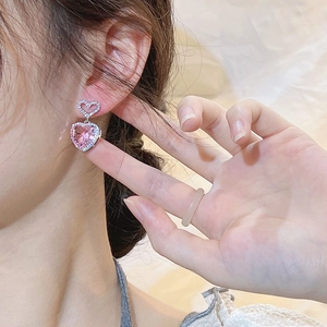 Elegant heart-shaped silver earrings with pink zircon stone worn by a female model