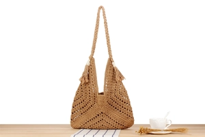Detail of khaki woven shoulder bag featuring bohemian tassels and hollow knit texture