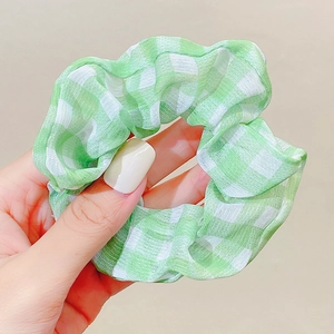 Detail of soft green and white checkered scrunchie showing fabric texture and pleats