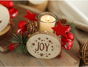 Close-up of wooden Christmas candle holder with JOY engraving and pinecone decor