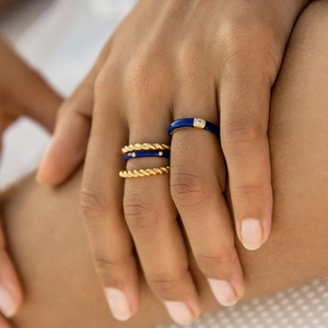 Close-up of four stacked gold rings with blue enamel and sparkling zircon accents