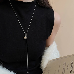 Detail of silver star pendant necklace on black knit sweater with a luxurious Y-shape drop