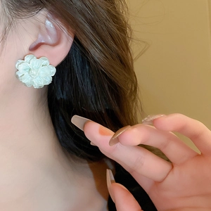 Close-up of light green floral acrylic earring worn on ear with multilayered petal design