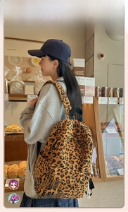 Side view of leopard print corduroy backpack on model in a cozy bakery setting