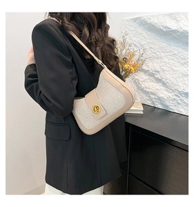 Detail of elegant beige crescent shoulder bag with leather trim and gold twist-lock