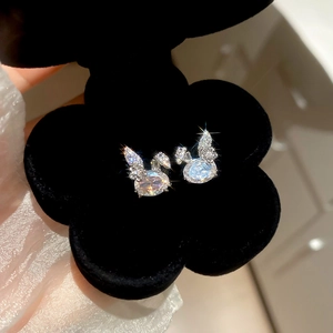 Close-up of a silver swan stud earring with zircon inlay in a black velvet flower box