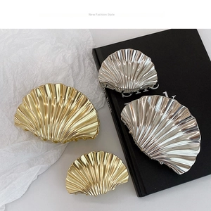 Macro detail of gold and silver shell hair claws with elegant wavy ripple textures