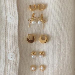 Detailed view of 925 sterling silver floral and pearl earrings set on white knitwear