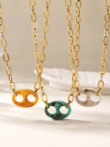 Close-up van gouden kettingen met ovale hars hangers in oranje, cyaan en wit marmer patroon