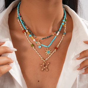 Gros plan du collier multicouche bohème avec turquoise, perles et pendentif soleil