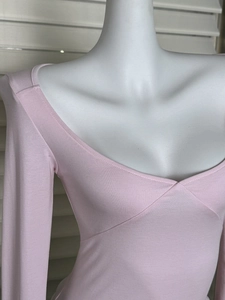 Close-up of the overlapping V-neckline and fine knitted texture of the pink slim T-shirt