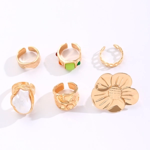 Detailed overhead view of six gold-tone rings set with baroque pearls and floral patterns