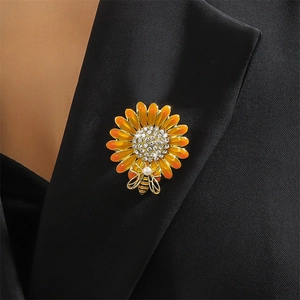 Orange daisy flower brooch with a gold bee and pearl accent on a black suit lapel