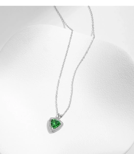 Macro detail of a heart-shaped emerald pendant with a halo of small diamonds