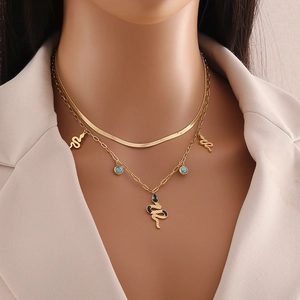 Close-up of double-layer gold snake pendant necklace with turquoise and black accents