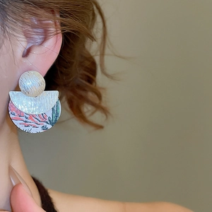 Gros plan de boucles d'oreilles asymétriques en bois avec peinture de cactus