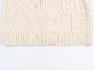 Detailaufnahme von cremefarbenem Strickpullover mit Rautenmuster und Rippbündchen