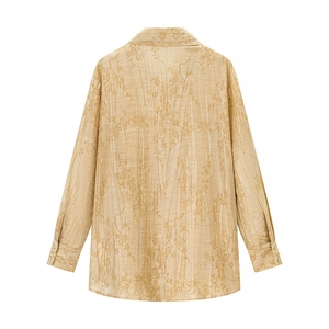 Dettaglio della trama floreale jacquard e del tessuto stropicciato della camicetta beige