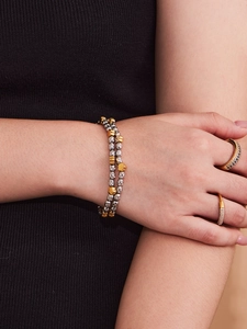Detailed shot of layered gold and silver bead bracelet with flower and heart charms