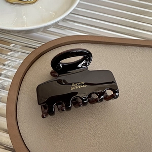 Detail of dark coffee acrylic hair claw clip with golden Barrette la France text