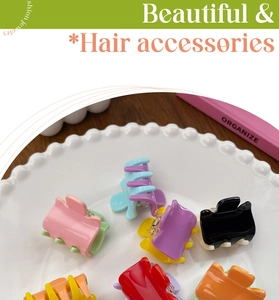 Close-up of candy colored mini hair claw clips in a white ceramic dish on wood surface