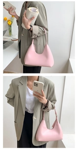 Detailed view of a soft pink PU leather underarm bag held by a model in a grey blazer