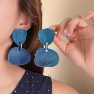 Close-up view of retro blue marble-patterned resin dangle earrings shown worn by a model