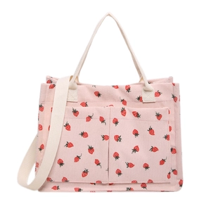 Pink corduroy tote bag with strawberry print, featuring front pockets and long shoulder strap