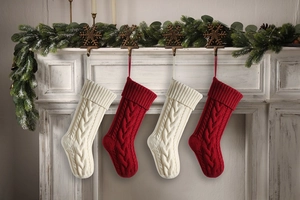 Close-up of red and beige cable knit Christmas stockings hanging on a white fireplace