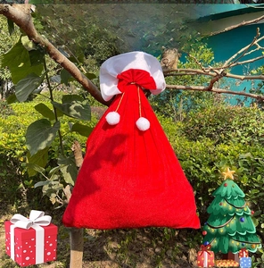 Detailed view of red velvet Christmas drawstring backpack with white fur trim and pom-poms